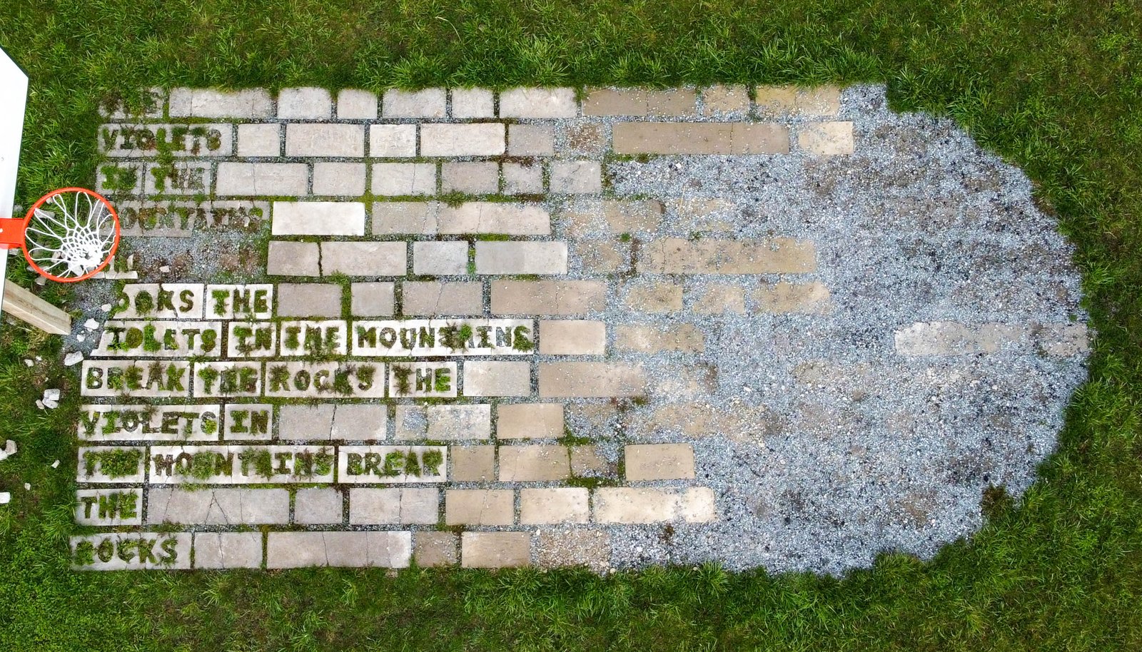 A concrete basketball key made up of pavers with text cut into them disintegrates into the ground
