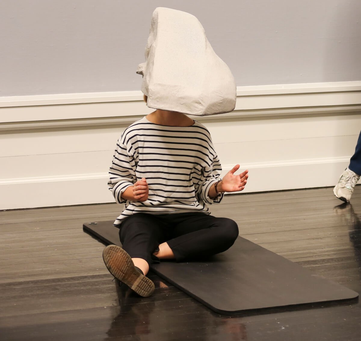 a person wearing a rock head sitting on a yoga mat